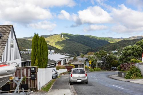 a car parked on a street with mountains in the background at Back Garden Flat with Free On Street Parking and Fiber WIFI - 15 mins to Ferry, Stadium, CBD in Wellington