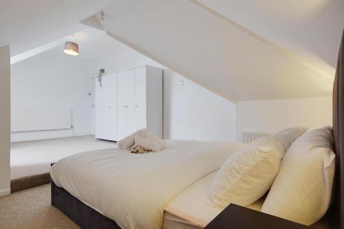 um quarto com uma cama grande e lençóis brancos em Ashley Road Apartment 3 em Poole