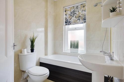 a bathroom with a tub and a toilet and a sink at Ashley Road Apartment 3 in Poole