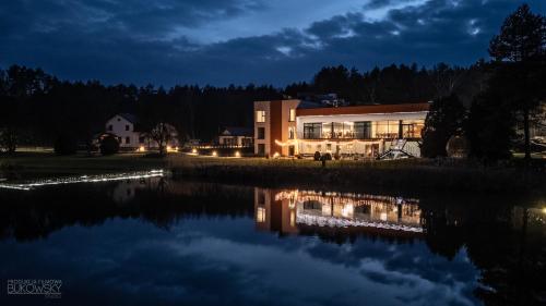 a building next to a lake at night at Hotel Odpocznia Resort i Las in Jaracz