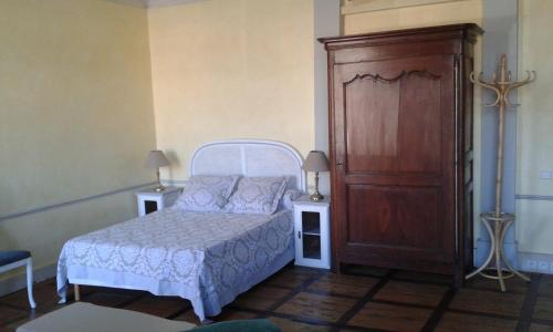 een slaapkamer met een wit bed en een houten kast bij Studio de Tourisme Tilleuls in Grenade-sur-lʼAdour