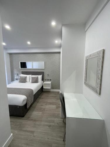 a bedroom with a bed and a table and a mirror at Chelsea Cloisters Serviced Apartments in London