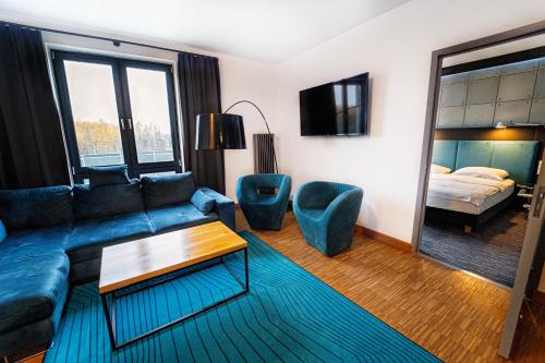 a living room with a blue couch and a bed at Artis Loft Hotel in Radziejowice