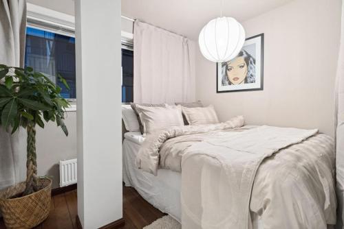 a white bedroom with a bed and a potted plant at Bryggeleilighet med balkong i Trondheim Sentrum in Trondheim