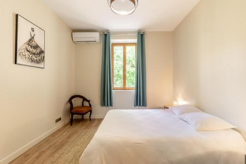 a bedroom with a white bed and a window at Le Château Olive et Raisin in Fontaine-de-Vaucluse