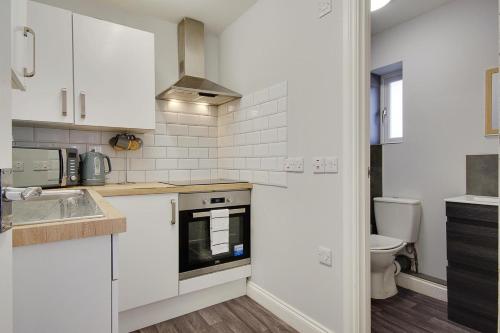a kitchen with white cabinets and a sink and a toilet at Ashley Road Apartments in Poole