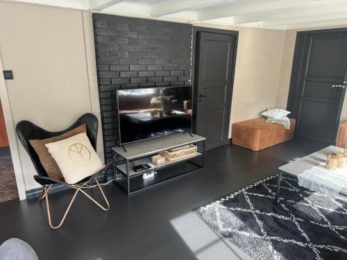 a living room with a fireplace and a chair at Nordbyhuset, et trivelig fritidshus in Skudeneshavn