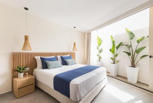 a bedroom with a bed with blue pillows and plants at Villa Iris, beachfront, with jacuzzi, up to 9 guests, Mpali beach, Rethymno! in Balíon