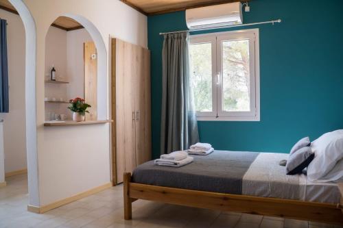 een blauwe slaapkamer met een bed en een raam bij Aroma Studios in Lakíthra