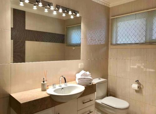 een badkamer met een wastafel, een toilet en een spiegel bij Cloud 9 Guest Suite in Burwood East