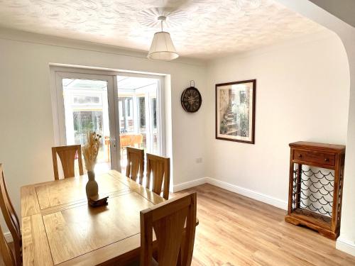a dining room with a table with chairs and a clock at Bilbo's Cottage, Sheringham in Sheringham