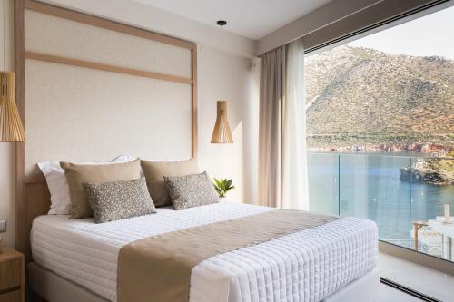 a bedroom with a bed and a large window at Villa Iris, beachfront, with jacuzzi, up to 9 guests, Mpali beach, Rethymno! in Balíon