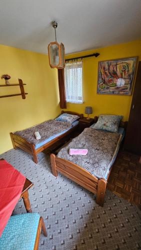 two beds in a room with yellow walls at Zajazd-restauracja Zyga in Iwkowa