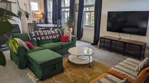 a living room with green couches and a flat screen tv at City Boho Loft Apartment Free Parking in Brighton & Hove