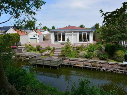 a house with a dock next to a body of water at Bungalow in Makkum near Lake Beach in Holle Poarte