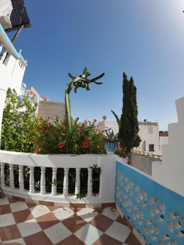 un balcón con flores y una valla blanca en CampSurf Morocco, en Tamraght Ouzdar