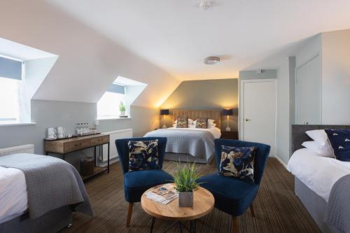 a hotel room with two beds and a table and chairs at Chester House Hotel in Bourton on the Water