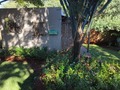 a sign for a house with a tree in a yard at Shangrila-innibos Country Lodge in Hartbeespoort