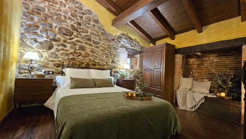 a bedroom with a large bed and a stone wall at La Clerecia de Ledesma in Ledesma