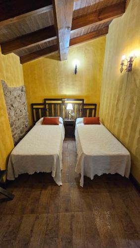 two beds in a room with yellow walls and wooden floors at La Clerecia de Ledesma in Ledesma