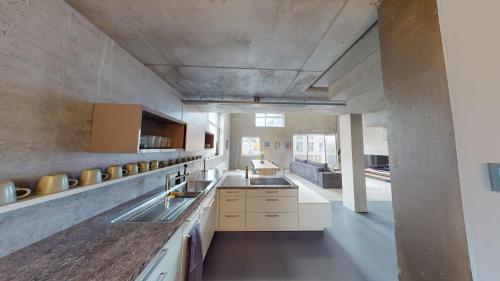 una grande cucina con armadi bianchi e parete di cemento di The Sunset Club - LOFT - 155 m2 Sichtbeton - Zentral a Memmingen