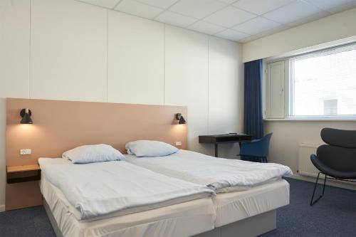 a bedroom with a bed and a desk and a chair at BB-Hotel Herning "Messehotel" in Herning
