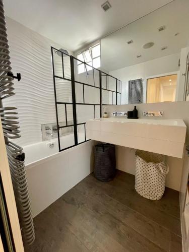 une salle de bain avec un lavabo, une baignoire et un miroir dans l'établissement Stylish modern large 2 Bedrooms 5 min close to Paris, à Levallois-Perret
