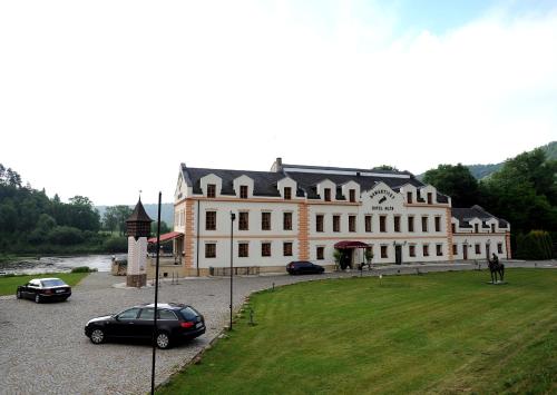 a large white building with cars parked in a parking lot at Romantic Hotel Mlýn Karlstejn in Karlštejn