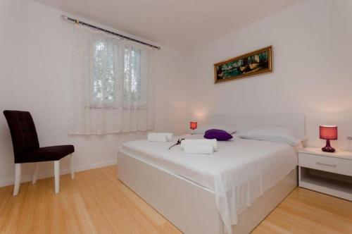ein weißes Schlafzimmer mit einem weißen Bett und einem Stuhl in der Unterkunft Happy Place in Podstrana
