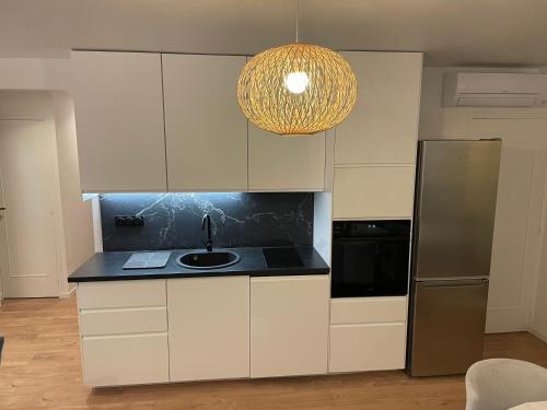 d'une cuisine avec des placards blancs, un évier et un lustre. dans l'établissement T3 Aperçu Mer, à Antibes