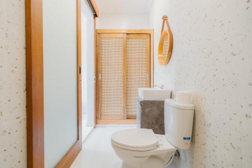 a white bathroom with a toilet and a window at Pondok Puspa Sumekar in Seminyak