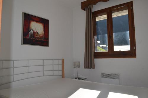 Habitación blanca con ventana y una foto en la pared. en Appartements montagne, piscine et sauna en Orelle
