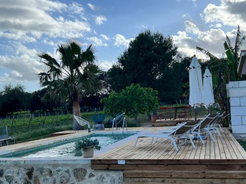 a pool with chairs and umbrellas on a wooden deck at Los Dos Caballeros Winery & Vacation Rental in Llubí