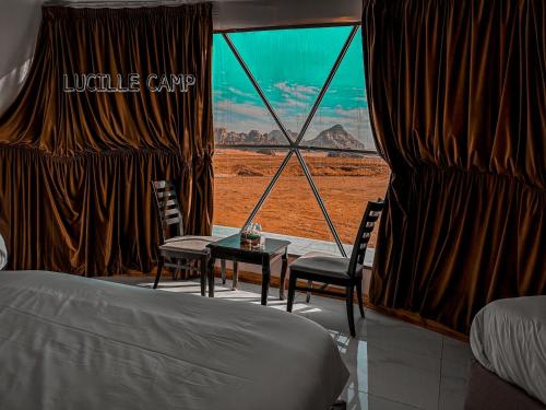 a bedroom with a bed and chairs and a view of the desert at Rum Lucille Luxury camp in Wadi Rum