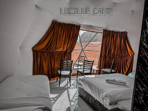 a bedroom with two beds and chairs and a window at Rum Lucille Luxury camp in Wadi Rum