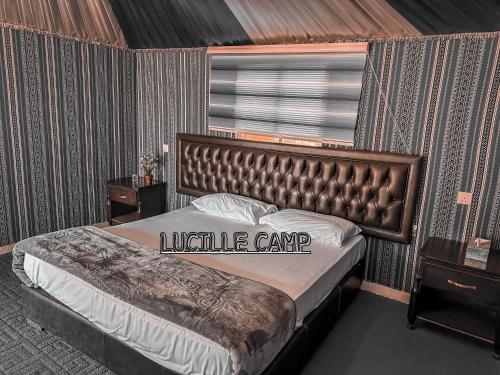 a bedroom with a large bed with a walille camp sign on it at Rum Lucille Luxury camp in Wadi Rum