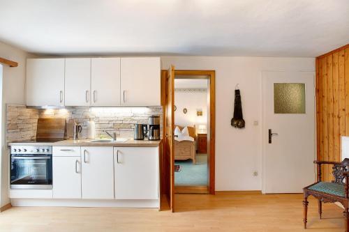 a kitchen with white cabinets and a door to a living room at Gästehaus Marianne - Ferienwohnung in Farchant
