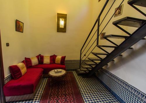 a living room with a red couch and a staircase at Riad Al Makan Fes & Spa in Fès