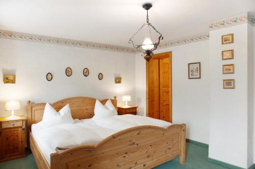 a bedroom with a wooden bed with white sheets at Gästehaus Marianne - Ferienwohnung in Farchant
