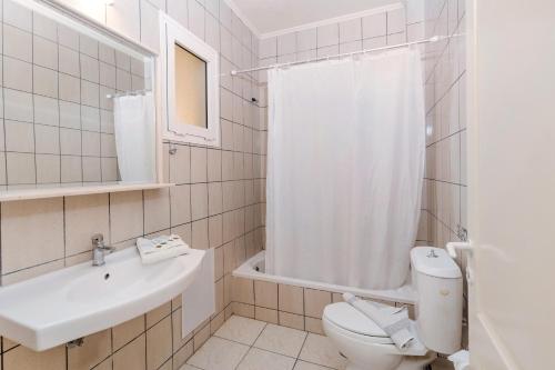 a white bathroom with a toilet and a sink at Eri Beach & Village Hotel in Hersonissos