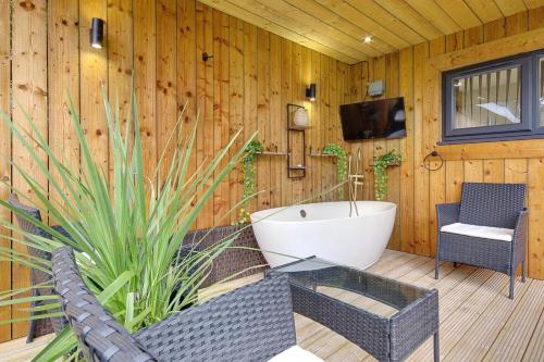 a bathroom with a tub and a tv on a wooden wall at Little Paddock in Ringwood