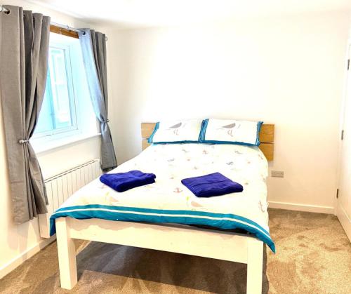 1 dormitorio con cama con sábanas azules y ventana en Harbour Lights Apartment New Quay, en New Quay
