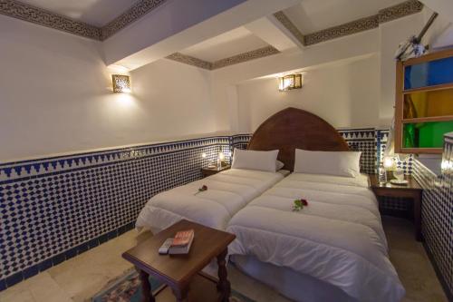 a hotel room with two beds and a table at Riad Al Makan Fes & Spa in Fès