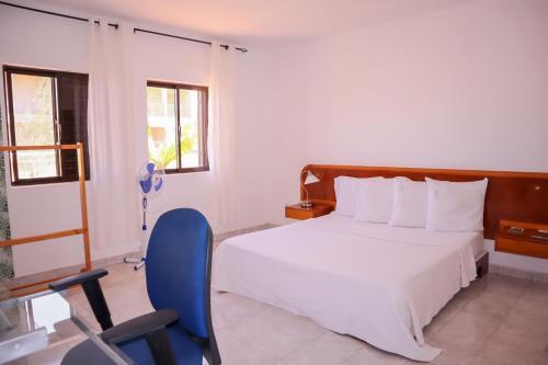 um quarto com uma cama e uma cadeira azul em Escape House em Tarrafal