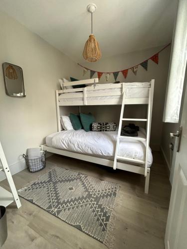 ein Schlafzimmer mit einem weißen Etagenbett mit einem Teppich in der Unterkunft Shoemakers Cottage in Ramsgate