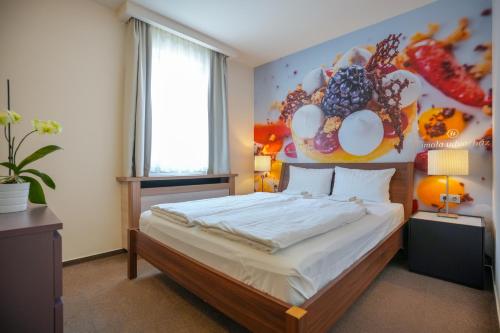Imola Udvarház Dessert Hotel في إغير: غرفة نوم بسرير مع لوحة على الحائط