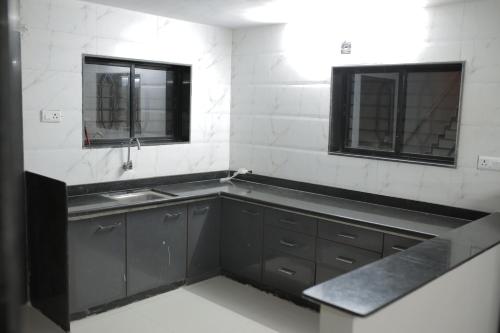 uma cozinha com armários pretos, um lavatório e duas janelas em Kookee Villa em Hātgarh