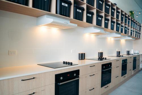 a kitchen with a row of counters and appliances at Capsuleaccom Hostel in Gold Coast