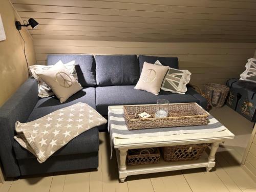 a blue couch with pillows and a table at Nordbyhuset, et trivelig fritidshus in Skudeneshavn