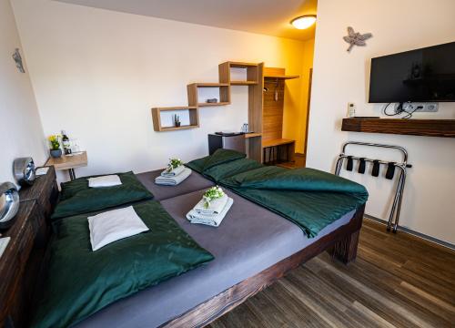 Habitación con 2 camas con sábanas verdes en Penzion Víno Hruška, en Veselí nad Moravou